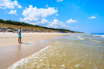 Young woman tourist walking along sea on Lubiatowo beach, Baltic Sea, Poland