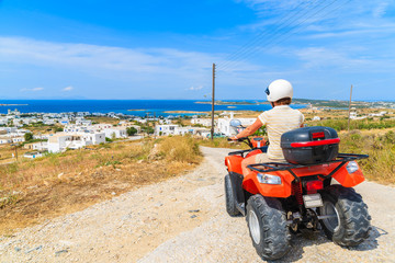 Young woman driving quad on gravel road on Paros island, Greece