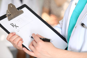 Close-up of a female doctor while filling up medical prescription