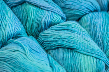 Many skeins of blue yarns are lying next to each other. Beautifully photographed with a diagonal composition.