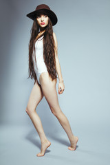 Beautiful girl with long hair in a white body suit and hat