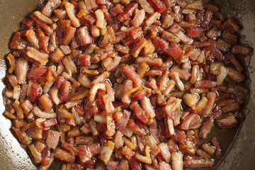 chopped pieces of pancetta frying in a skillet