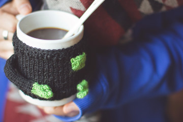 Fototapeta na wymiar Knitted woolen cup in female hands