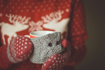 Knitted woolen cup in female hands