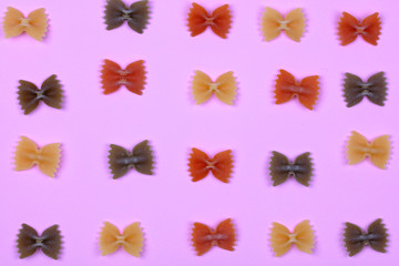 Colorful pattern made of pasta on pink background. Cooking pasta background, flay lay