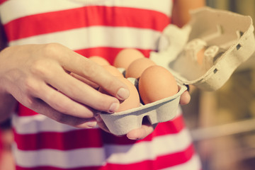 Hands holding shopping box of eggs. Closeup view