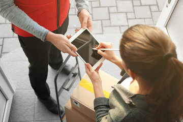 Young woman appending signature after receiving parcel from courier, closeup