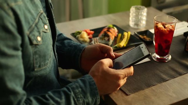 Man's hands are tuching tablet in sushi bar
