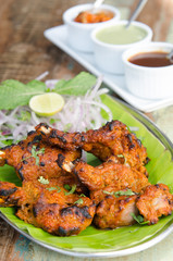 Delicious tandoori chicken starter, served with lime, onion, mint, yoghurt and sauces, on a banana leaf base...