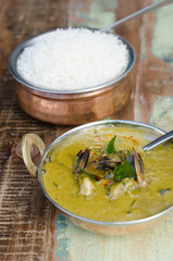A delicious spicy prawn green curry, served with sticky rice in a rustic metal pan.