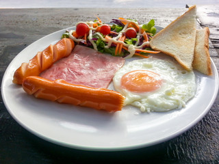 Breakfast foods - fried egg, bacon, sausages breads and vegetabl