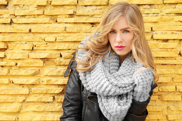 Young beautiful woman standing on yellow brick wall background