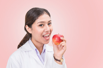 Young Asian female doctor eat apple isolated on pink background.