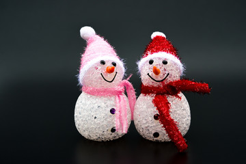 two smiling toy christmas snowman on black background