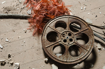 Naklejka premium An old metal rusty cinematography cinema film reel, that has been left in an abandoned cinema amongst concrete debris.