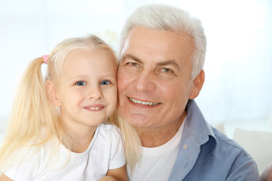 Cute happy girl with grandfather at home