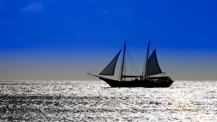 Fototapeta na wymiar Sailboat on sea navigating towards the sunset