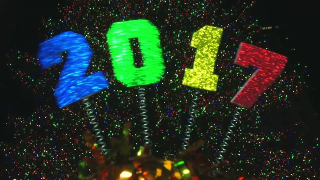 Decorative springy 2017 message for New Year on novelty headwear swaying against colorful bokeh light bubbles 
