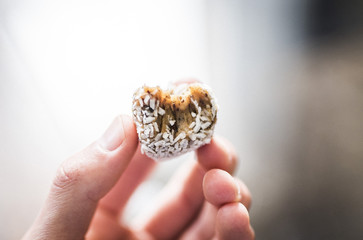 Fingers holding a raw vegan coconut-date ball