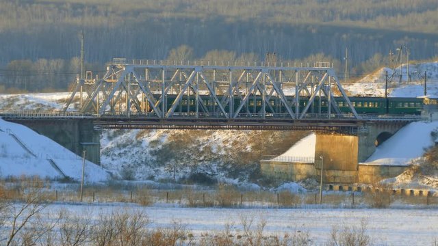 The train goes through railway bridge. Winter landscape