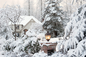 Driveway light and suburban house on a snowy Winter morning