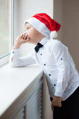 kid in a santa hat and bow tie at the window