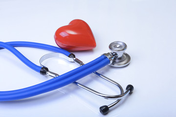 Cardiogram with stethoscope and red heart on table, closeup