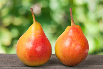 two pears on a dark wooden table with blurred background