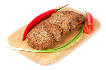 liver pancakes or cutlets with chilli and spring onions on a cutting board isolated white background