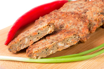 liver pancakes or cutlets with chilli and spring onions on a cutting board close-up isolated white background