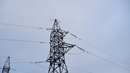 Electrical tower with cables against the gray electricity background