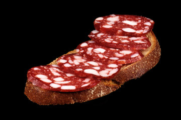 Smoked sausage and bread on a black background