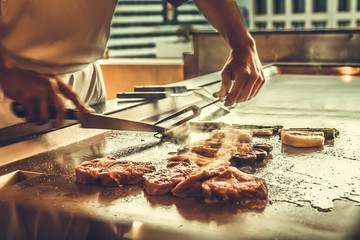 Fototapeta na wymiar Close up hands chef cooking beef steak and vegetable on hot pan, Japanese food