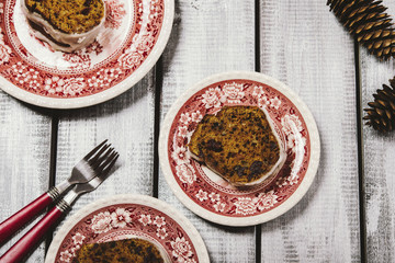 Spicy Pumpkin Cake with nuts and cranberries drizzled icing cut into pieces in bright painted plates on the wooden background with fir cones. Selective focus. Toned image 