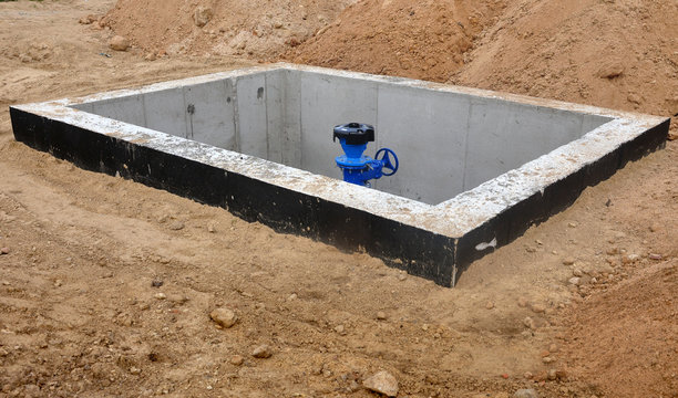 The construction process of node to connect cold water supply. The rectangular concrete box dug into the sand and distribution setting inside.