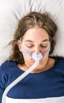 Woman sleeping on her back with CPAP, sleep apnea treatment. Portrait taken from above.