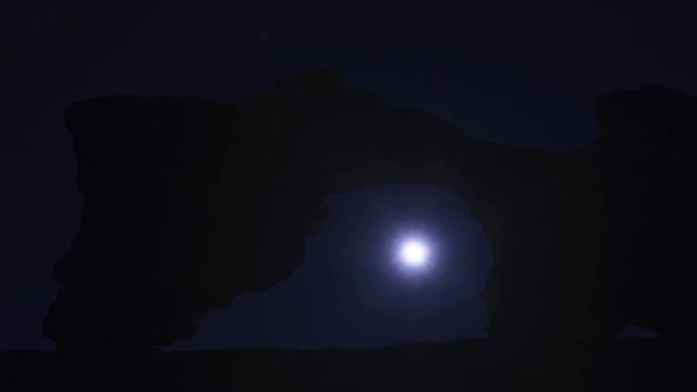 Timelase of Moon Passing Through Tukuhnikivatz Arch near Arches National Park and  Moab, Utah USA