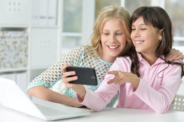 two girls with phone and laptop