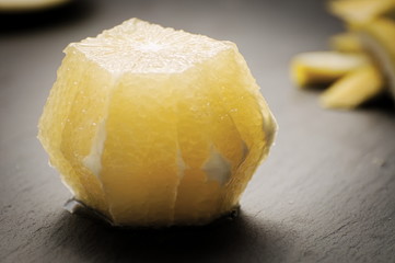 Peeled organic bittersweet grapefruit with zest on dark backgrou