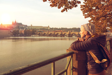 A young woman is looking at the sunset over a river Vltava in th