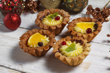 Homemade desserts with fruits for the new year. Desserts for the holidays. View from above. Christmas decorations and toys. The desserts on the wooden background.