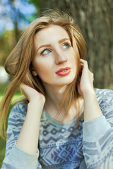 Portrait of a young girl with blue eyes who is sitting in the park