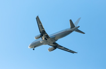 Fototapeta na wymiar white airplane flying in a clear pale blue sky.