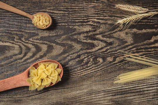Pasta,  spaghetti and wheat on a wooden background.