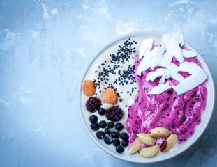 Breakfast purple berry smoothie bowl on a concrete background. Love for a healthy raw food concept.