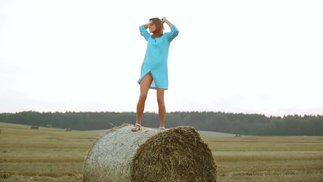 Beautiful young woman dancing in a haystack.