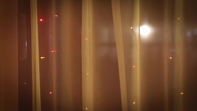Christmas lights in the window on the background of transparent tulle.