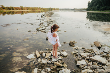 a little girl standing on stones by the river
