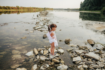 a little girl standing on stones by the river