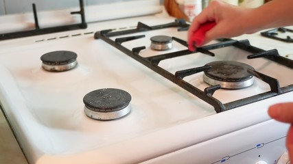 woman washes a gas stove in cleaning the kitchen